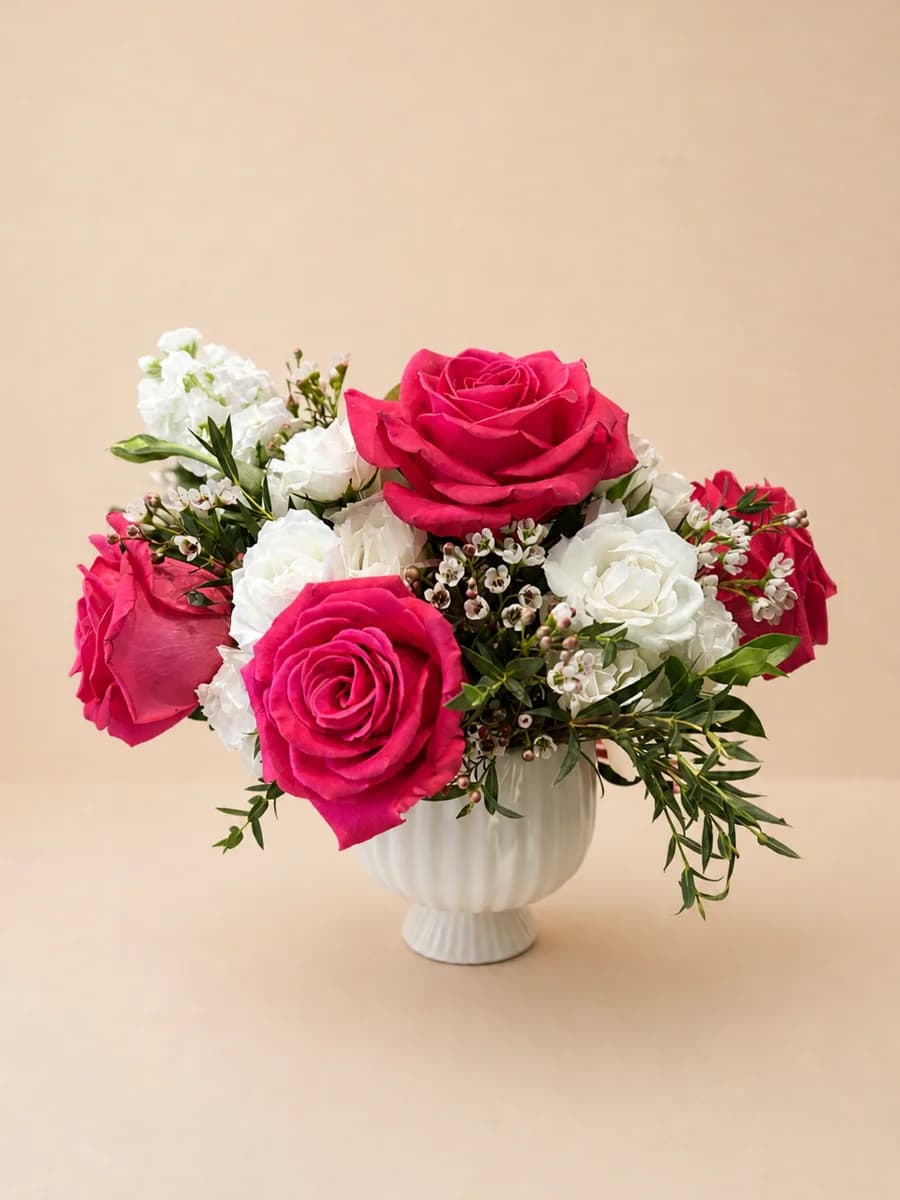 The Juliette - hot pink roses and spray roses with wax flowers and eucalyptus in a white scalloped vase