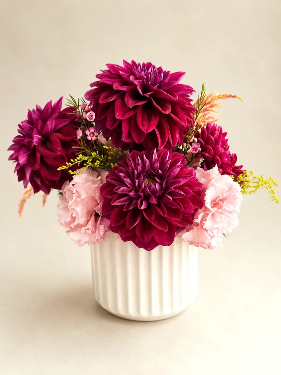 The Odette - burgundy dahlias with pink lisianthus and waxflower in a white ribbed ceramic vase