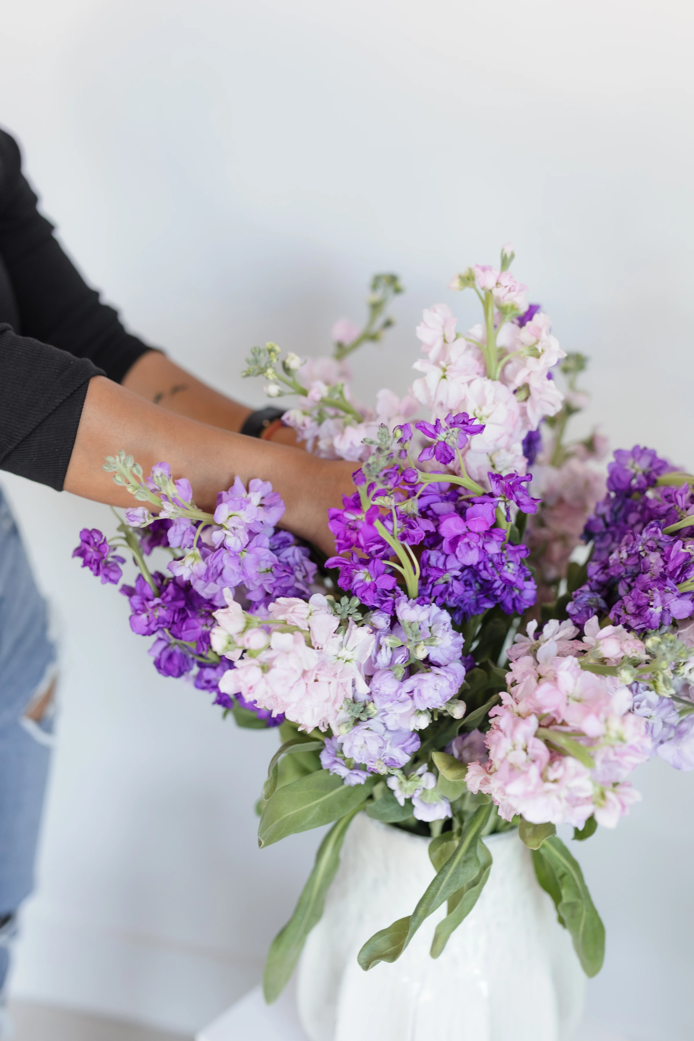 Hands arranging lavender and purple stock flowers