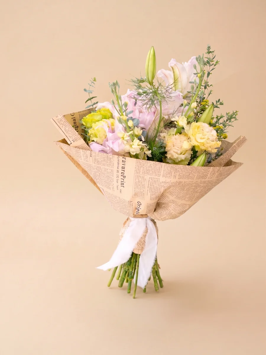 The Adeline - hand-tied garden bouquet of yellow stock, pink double lilies, and pink lisianthus wrapped in artisan paper