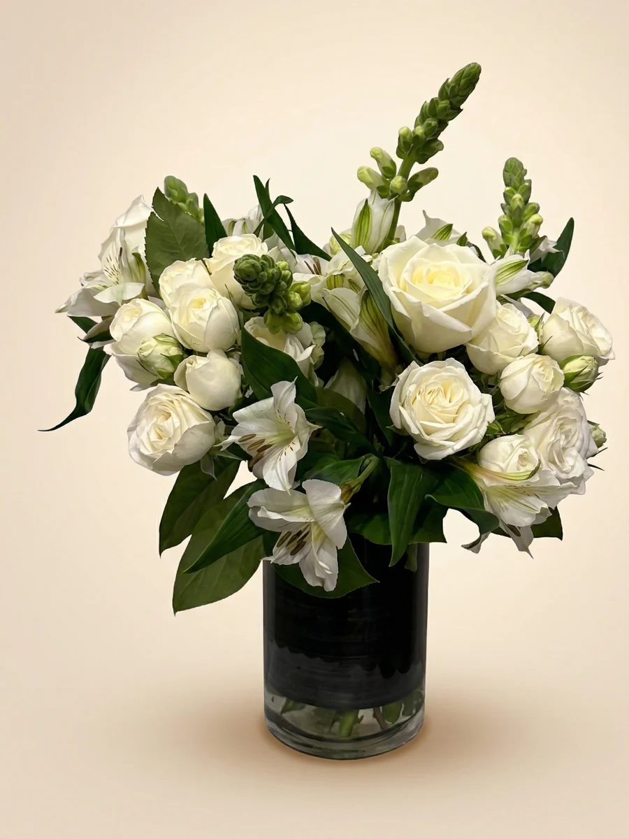 The Serenity - all-white sympathy flower arrangement with roses, lilies, and snapdragons in a ceramic vase